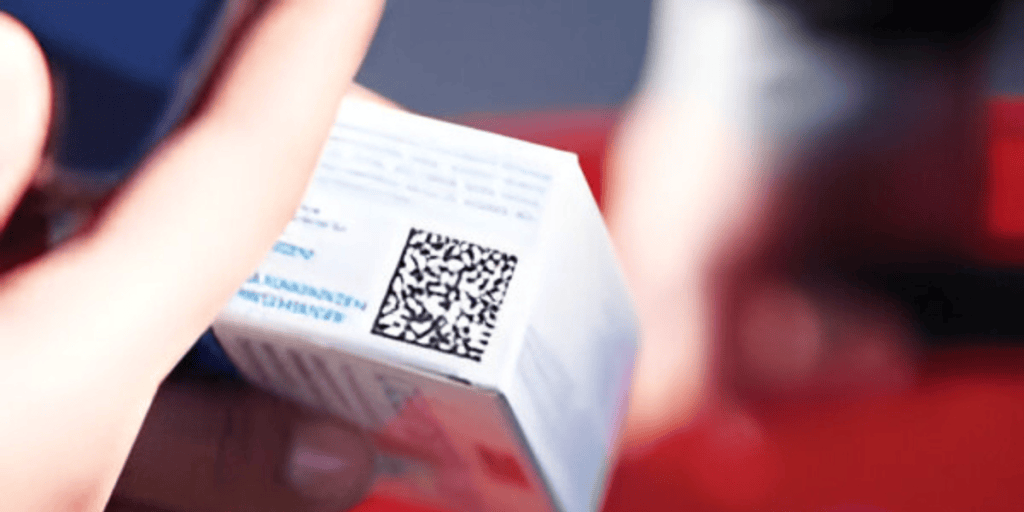 A close-up of a person holding a product box with a visible QR code on it.