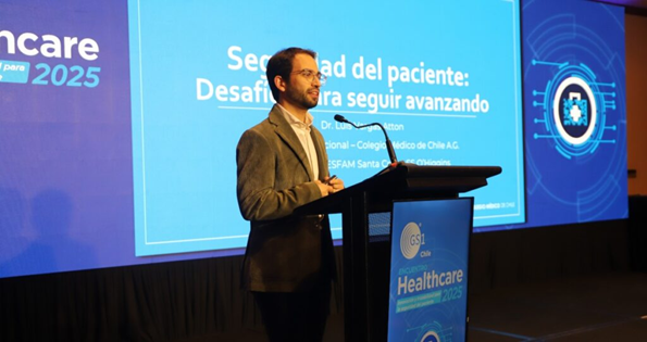 Dr. Luis Vargas presentando sobre seguridad del paciente en el Encuentro Healthcare 2025 en Chile, con una pantalla atrás que muestra su tema.