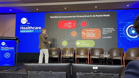 Ponente presentando en el Encuentro Healthcare 2025 en Chile, con una pantalla detrás que muestra gráficos sobre desafíos en el proceso de I+D para IA en el Hospital de Puerto Montt.