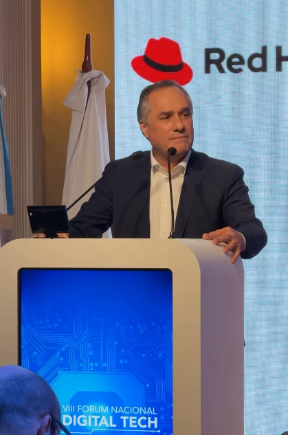 Un orador en el VIII Fórum Nacional Digital Tech, con un escenario decorado con logos tecnológicos y banderas argentinas.